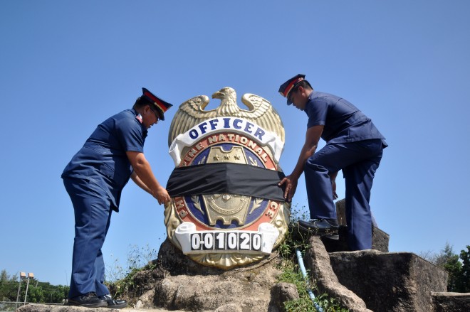 Officers of the Pangasinan Police Office in Lingayen town in Pangasinan province tie a black cloth around a giant police badge in the camp's park to join the nation in mourning the 44 members of the Special Action Force who were brutally killed in Maguindanao province. WILLIE LOMIBAO/CONTRIBUTOR
