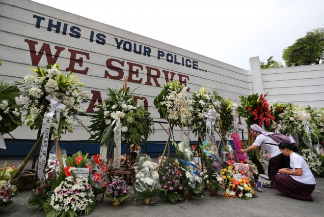 Sisters (from the Religious of the Assumption) leave flowers and light candles to show their sympathy for the slain 44 PNP SAF troopers outside the gates of Camp Crame in Quezon City. RAFFY LERMA/INQUIRER