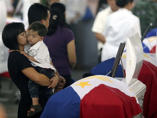 Christine Kiangan, widow of Noble Kiangan, one of the 44 members of the elite police commandos killed last Sunday during the Philippines' biggest single-day combat loss in recent years, kisses her son in front of her husband's flag-draped coffin at Camp Bagong Diwa, Taguig city on Friday, Jan. 30, 2015.  Bullit Marquez/ASSOCIATED PRESS