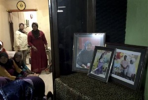 In This Thursday Jan. 1, 2015 photo, framed pictures, from left, of Soemanik Saeran, 64, Naura Kanita Rosada Suseno, 9, and Djoko Suseno, 43 with his wife Hayati Lutfiah Hamid, 39, are displayed in the home of Soemanik where relatives and friends have gathered for nightly prayers, in Surabaya, Indonesia. AP