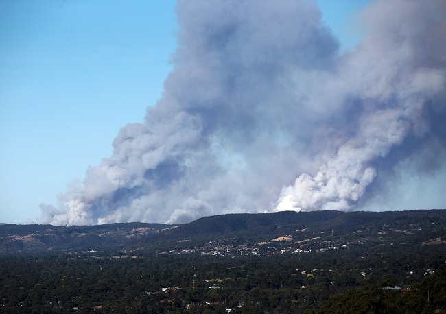In this Friday, Jan. 2, 2015 photo released by China's Xinhua News Agency, heavy smoke billow in the Adelaide Hills, Australia. A dozen homes have been destroyed by the fire in the Adelaide Hills in South Australia, with another 20 also feared lost, state Premier Jay Weatherill said. Cooler conditions on Sunday, Jan. 4 were helping hundreds of firefighters working to contain a massive wildfire that had forced thousands of people to flee their homes in southern Australia. AP