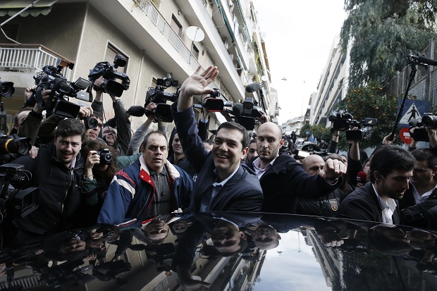 Alexis Tsipras, center, leader of Greece's Syriza left-wing main opposition waves to his supporters after voting at a polling station in Athens, Sunday, Jan. 25, 2015. Greeks were voting Sunday in an early general election crucial for the country's financial future, with the radical left Syriza party of Alexis Tsipras tipped as the favorite to win, although possibly without a large enough majority to form a government.  (AP Photo/Petros Giannakouris)