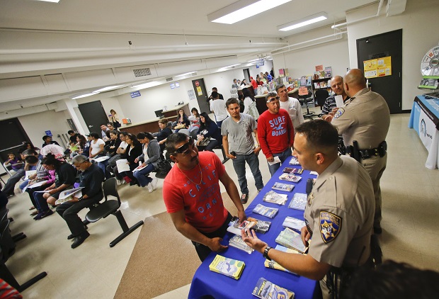 FILE - In this April 23, 2014, file photo, California Highway Patrol officers Armando Garcia, right, and Ray Patton explain to immigrants the process of getting a drivers license during an information session at the Mexican Consulate, in San Diego. California is gearing up to start issuing driver’s licenses to immigrants in the country illegally in a bid to make the roads safer that could also give more than a million people access to state-issued identification.  AP