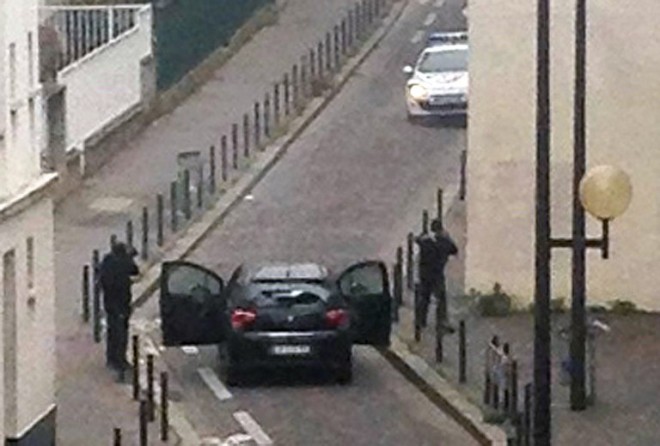 Armed gunmen face police officers near the offices of the French satirical newspaper Charlie Hebdo in Paris on January 7, 2015, during an attack on the offices of the newspaper which left eleven dead, including two police officers, according to sources close to the investigation. AFP 