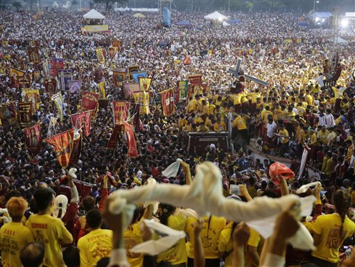 Filipino devotees wave handkerchiefs to cheer the image of the Black Nazarene (top right) during its annual procession to celebrate its feast day Friday, Jan. 9, 2015 in Manila, Philippines. The raucous celebration drew tens of thousands of devotees in a barefoot procession around Manila streets.  AP