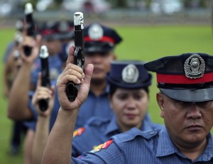 Philippine police show their pistols that were taped at the muzzle at Camp Crame in suburban Quezon City, north of Manila, Philippines on Monday, Dec. 22, 2014. Police were ordered to have their firearms tapped and signed by their leaders to prevent them from firing during the Christmas and New Year revelry. Firing of guns in the air during the celebrations has led to numerous deaths from stray bullets in the past. AP FILE PHOTO