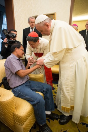 Pope Francis and Cardinal Luis Antonio Tagle meet the father of a young Catholic volunteer who was killed Saturday while helping organize his Mass in typhoon-hit Tacloban, in Manila, Philippines, Sunday, Jan. 18, 2015. The Vatican said Francis met Sunday for about 20 minutes with the girl's father at the Vatican Embassy in Manila. Police said Kristel Padasas, a volunteer with Catholic Relief Services, died when scaffolding fell on her. Witnesses said a sudden gust of wind toppled the structure, which served as platform for a large loudspeaker during the Mass. (AP Photo/L'Osservatore Romano, Pool)