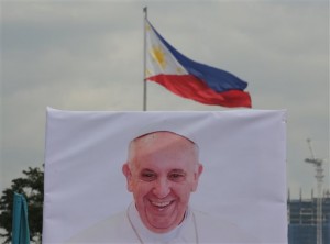 A photo of Pope Francis stands in front of a Philippine national flag as preparations for his visit continue at Manila's Rizal park, Philippines, Sunday, Jan. 11, 2015. AP
