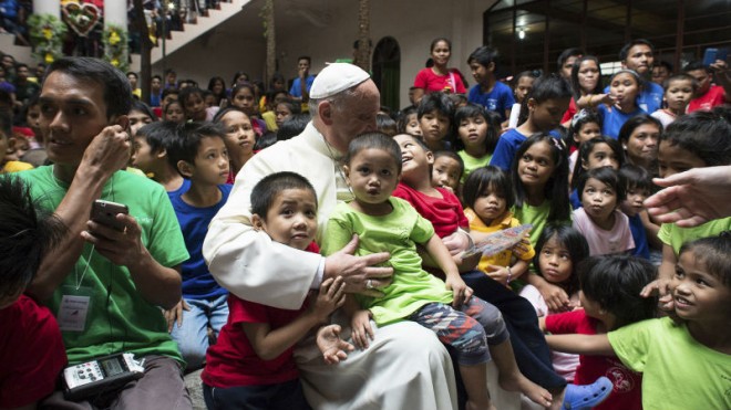 Pope Francis sits with children of the Anak-Tnk Foundation, founded in 1998 by a Jesuit priest, which helps homeless children and those living in the slums, in Manila's Intramuros district after celebrating Mass at the nearby Manila Cathedral, in Manila, Philippines, Friday, Jan. 16, 2015. Some 300 children at a Manila center for street kids got the surprise of their lives on Friday when Pope Francis showed up at their door. (AP Photo/Osservatore Romano, Pool)
