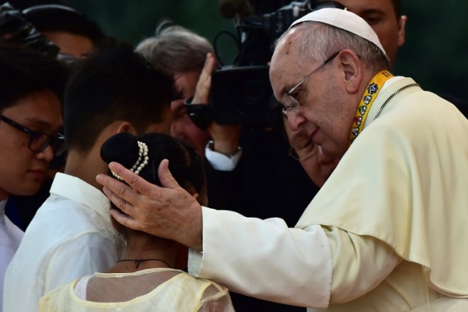 Pope Francis reaches out to Jun Chura, 14, and Glyzelle Iris Palomar, 12,during his visit to the University of Santo Tomas in Manila on January 18, 2015.  AFP PHOTO/GIUSEPPE CACACE