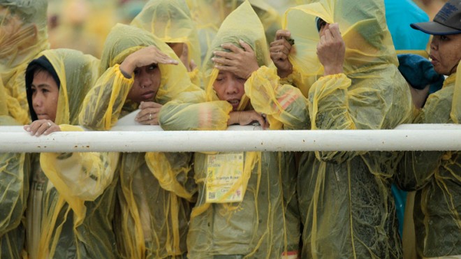 The faithful brave the heavy rain and strong winds as they listen to a mass delivered by Pope Francis in Tacloban, Philippines, Saturday, Jan. 17, 2015. A rain-drenched but lively crowd wearing yellow and white raincoats welcomed Pope Francis in the typhoon-ravage central Philippine city of Tacloban early Saturday, chanting "Papa Francesco, Viva il Papa!" (AP Photo/Wally Santana)