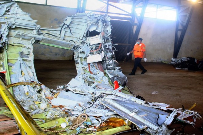 In this photograph taken on Jan. 19, 2015, a member of Indonesia's search and rescue team walks past wreckage of AirAsia flight QZ8501 recovered at sea and stored in a warehouse for investigators in Kumai, Central Kalimantan on Borneo island. Analysts said on Wednesday, Jan. 21, that revelations that AirAsia Flight QZ8501 climbed too fast before stalling and plunging into the sea point to "striking" similarities between the Java Sea accident and the 2009 crash of an Air France jet.  AFP PHOTO/YUDHA MANX
