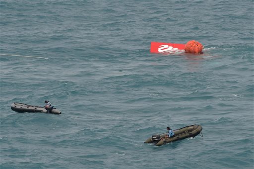 Portion of the tail of AirAsia Flight 8501 floats on the water as Indonesian navy divers conduct search operations for the black boxes of the crashed plane in the Java Sea, Indonesia, Saturday, Jan. 10, 2015. Investigators searching for black boxes in the crashed AirAsia plane lifted the tail portion out of the Java Sea on Saturday, two weeks ago after it went down, killing all 162 people on board. (AP Photo/Adek Berry, Pool)