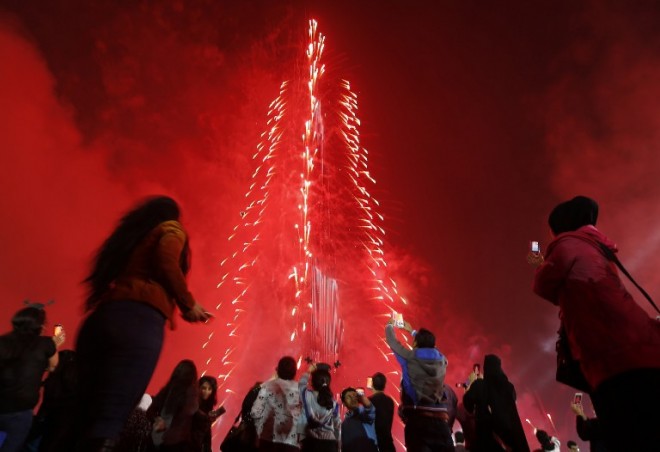 People watch as Dubai celebrates the New Year with a light and sound extravaganza at midnight at the Burj Khalifa, the world's tallest tower on Jan. 1, 2015.  AFP PHOTO/KARIM SAHIB