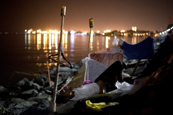 A homeless man sleeps along the Manila Bay on Saturday, Jan. 24, 2015. the House of Representatives will investigate the Department of Social Welfare and Development in connection with its hauling off hundreds of street children and homeless people to detention centers and beach resorts during the recent visit of Pope Francis to the Philippines.  AFP PHOTO / NOEL CELIS