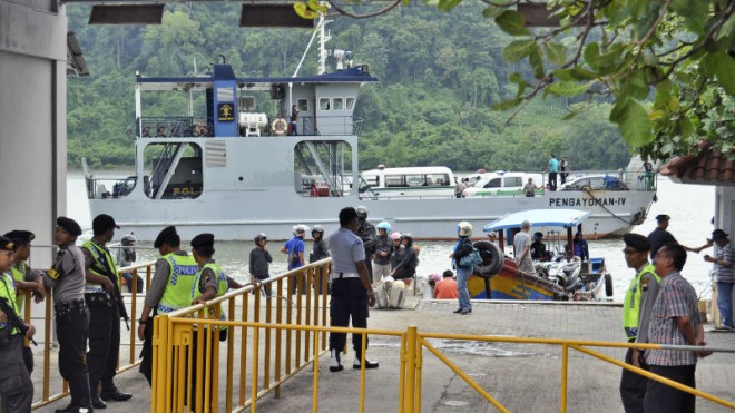 Police officers and security personnel stand guard as a ferry carrying ambulances sets off for Nusakambangan island where the executions of the five of six drug convicts will be performed, at Wijayapura port in Cilacap, Central Java, Indonesia, Saturday, Jan. 17, 2015. Five foreigners and an Indonesian woman sentenced to death on drug charges will be executed by firing squad despite international pleas, Indonesian officials said Saturday. (AP Photo/Wagino) 
