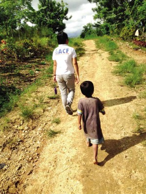 A WORKER of international children’s aid group ACF walks with Mark Real Jay “Emman” Luwas, a boy who was barely alive until the group found and helped nourish him. NICO ALCONABA