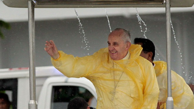 Wearing a yellow raincoat, Pope Francis waves to the faithful as he arrives in Tacloban, Philippines, Saturday, Jan. 17, 2015. A rain-drenched but lively crowd wearing yellow and white raincoats welcomed Pope Francis in the typhoon-ravage central Philippine city of Tacloban early Saturday, chanting "Papa Francesco, Viva il Papa!" (AP Photo/Wally Santana)