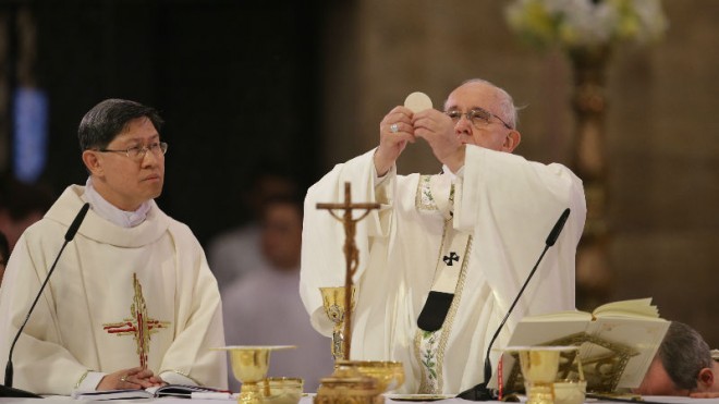 Pope Francis, right, lifts the host beside Cardinal Luis Antonio Tagle, archbishop of Manila, as he officiates a mass with clergy and religious at the Cathedral Basilica of the Immaculate Conception in Manila, Philippines, Friday, Jan. 16, 2015. (AP Photo/Aaron Favila)