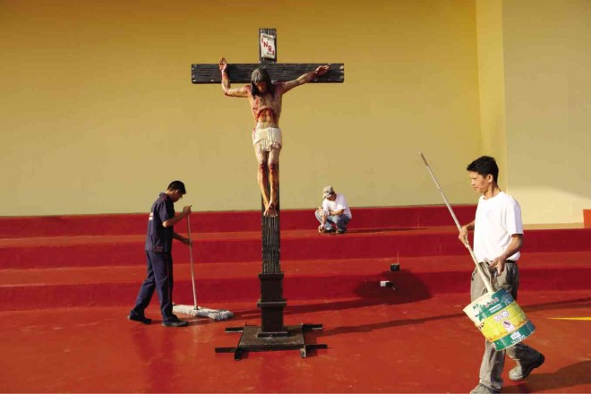READYING UST  Around a life-size image of the Crucifixion, workers on Wednesday prepare the stage on the University of Santo Tomas campus in Manila where Pope Francis is scheduled to address youths and religious leaders on Sunday, Jan. 18, as part of his five-day visit to the country.  JOAN BONDOC