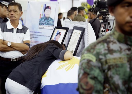 Erica Pabalinas, widow of Police Senior Inspector Ryan Pabalinas, mourns before the flag-draped coffin of her late husband, who along with 43 others perished last Sunday during the Philippines' biggest single-day combat loss in recent years, at Camp Bagong Diwa, Taguig city, south of Manila, Philippines, on Friday, Jan. 30, 2015.  AP