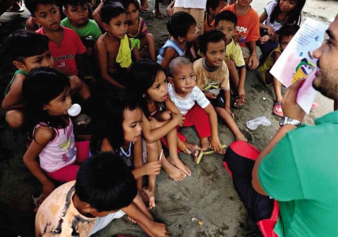CHILDREN intently listen to Rey Bufi of The Storytelling Project as he talks about a story from the book “Super Labandera,” which his group produced. CHA MALAZARTE/CONTRIBUTOR 