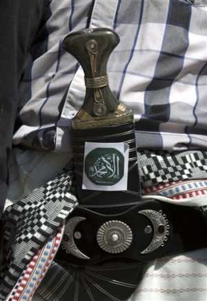 A Yemeni man pasts a sticker on his traditional al-Janbiah dagger with Arabic writing of "Nothing but Muhammad" during a protest against caricatures published in French magazine Charlie Hebdo in front of the French Embassy in Sanaa, Yemen, Saturday, Jan. 17, 2015. AP 