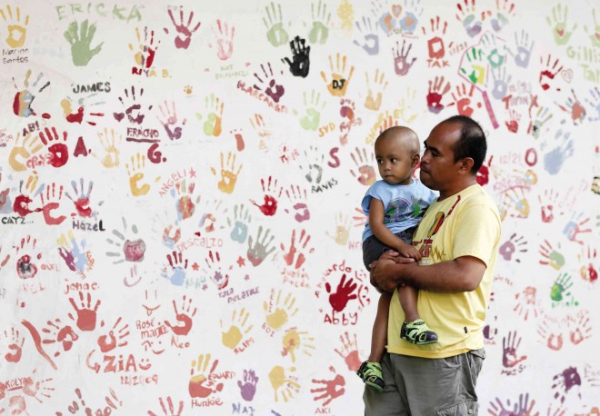 PLAYTIME AMID PAIN A young boy and his father wait for their appointment at the Cancer and Hematology Center of the Philippine Children’s Medical Center in Diliman, Quezon City, where a section of the wall bears the names and hand imprints of past patients. LYN RILLON 