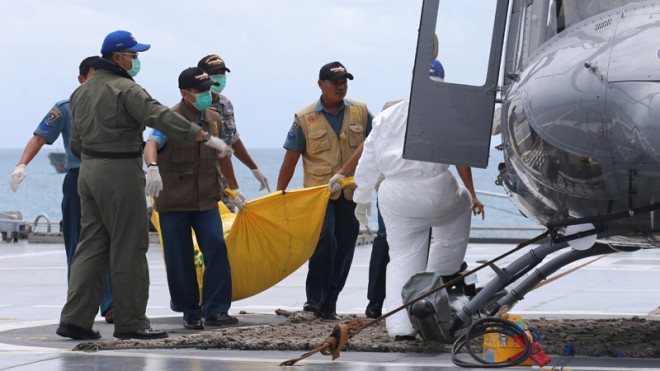Military personnel load a bodybag containing what they believe to be a victim of AirAsia QZ 8501 onto a helicopter on the deck of Indonesian Navy ship KRI Banda Aceh sailing in the Java Sea, Indonesia, Thursday, Jan. 22, 2015. Indonesian divers retrieved Thursday six more bodies from waters around the sunken fuselage of the AirAsia jetliner that crashed last month. (AP Photo/Natanael Pohan)