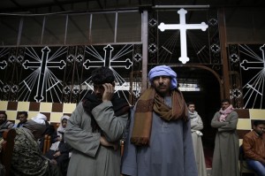 Men mourn over the Egyptian Coptic Christians who were captured in Libya and killed by militants affiliated with the Islamic State group, at the Virgin Mary church in the village of el-Aour, near Minya, 220 kilometers (135 miles) south of Cairo, Egypt, Monday, Feb. 16, 2015. Egyptian warplanes struck Islamic State targets in Libya on Monday in swift retribution for the extremists' beheading of a group of Egyptian Christian hostages on a beach, shown in a grisly online video released hours earlier. (AP Photo/Hassan Ammar)