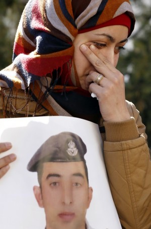 Anwar al-Tarawneh, the wife of Jordanian pilot, Lt. Muath al-Kaseasbeh, who is held by Islamic State group militants, holds a poster of him as she weeps during a protest in Amman, Jordan, Tuesday, Feb. 3, 2015. An online video released Tuesday, Feb. 3, 2015 purportedly shows a Jordanian pilot captured by the Islamic State extremist group being burned to death. The Associated Press was not immediately able to confirm the authenticity of the video, which was released on militant websites and bore the logo of the extremist group's al-Furqan media service. (AP Photo/Raad Adayleh)