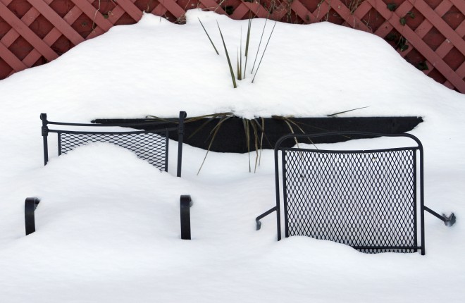 Patio furniture sit mostly buried in a mound of snow Friday, Feb. 13, 2015, behind a restaurant in downtown Boston. Another winter storm that could bring an additional foot or more of snow to some areas is forecast for the region beginning Saturday evening.  AP PHOTO/BILL SIKES 