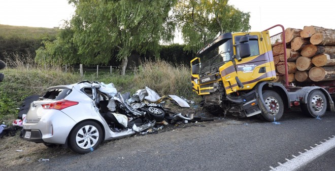 In this Tuesday Feb. 17, 2015 photo, a car and a logging truck sit damaged after they collided head-on near Tokoroa, New Zealand. New Zealand authorities said Thursday, Feb. 19 that U.S. citizens Warren Lee, his wife Aesoon Lee and the couple's daughter, Julia Lee were killed and their son critically injured when their car crashed into the logging truck. AP
