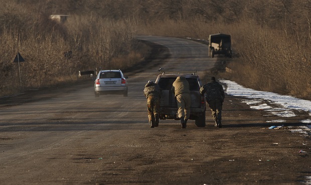 Ukrainian troops push a car as tehy attempt to start it, outside Artemivsk, Ukraine, while pulling out of Debaltseve, Wednesday, Feb. 18, 2015. After weeks of relentless fighting, the embattled Ukrainian rail hub of Debaltseve fell Wednesday to Russia-backed separatists, who hoisted a flag in triumph over the town. The Ukrainian president confirmed that he had ordered troops to pull out and the rebels reported taking hundreds of soldiers captive.(AP Photo/Vadim Ghirda)