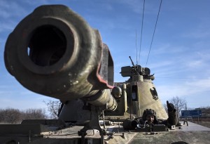 A Ukrainian soldier smiles riding on a self-propelled artillery piece near Artemivsk, eastern Ukraine, Monday, Feb. 23, 2015. A Ukrainian military spokesman says continuing attacks from rebels are delaying Ukrainian forces' pullback of heavy weapons from the front line in the country's east. (AP Photo/Evgeniy Maloletka)