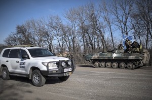 A car of Organization for Security and Co-operation in Europe (OSCE) mission drives past a Ukrainian military vehicle near Artemivsk, eastern Ukraine, Monday, Feb. 23, 2015.  Ukraine delayed a promised pullback of heavy weapons from the front line Monday in eastern Ukraine, blaming continuing attacks from separatist rebels.  (AP Photo/Evgeniy Maloletka)