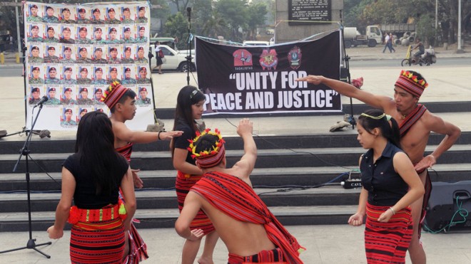 Indigenous students call for "Unity for Peace and Justice" as they perform an Ifugao ritual dance in Manila on Feb. 7, 2015, in front of a display of photos showing the 44 elite commandos who died in a police raid in Mamasapano town, in the southern island of Mindanao during a mission in January to capture one of the world's most wanted terrorists, Bali bomber Zulkifli bin Hir.  AFP PHOTO/Jay DIRECTO