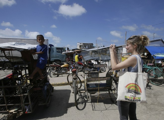 French actress Melanie Laurent photographs a boy during her visit as part of French President Francois Hollande's entourage to the typhoon-ravaged Guiuan township, Eastern Samar province in central Philippines Friday, Feb. 27, 2015. Hollande's two-day state visit focuses on climate change. AP