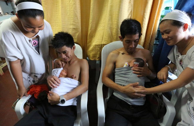 The fathers, Mark Anthony Padilla  with wife Jessa  and Mark Falcon  with wife Jane   with their newly born babies does  the Kangaroo father care inside the Jose Fabella hospital during World Health Organization hospital tour  for the launching of  the "Unang Yakap"  in the Western Pacific Region.  INQUIRER PHOTO/JOAN BONDOC