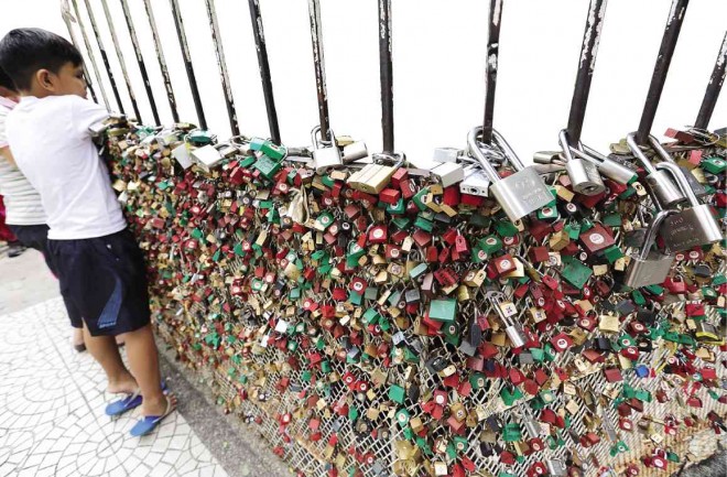 SEALED WITH PRAYERS  The fence around a grotto outside Baclaran Church in Parañaque City is now heavy with “symbols’’ of relationships seeking heaven’s blessing.JOAN BONDOC 