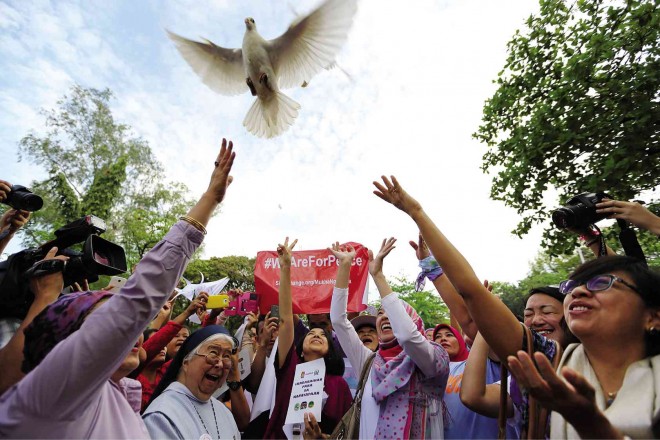 LET IT FLY  Peace advocates release a dove on Friday, the first anniversary of the signing of the Comprehensive Agreement on the Bangsamoro during the Women’s March for Peace attended by government peace panel chair Miriam Coronel-Ferrer (right), nuns, Muslims, artists and female police officers at Quezon Memorial Circle. RAFFY LERMA 