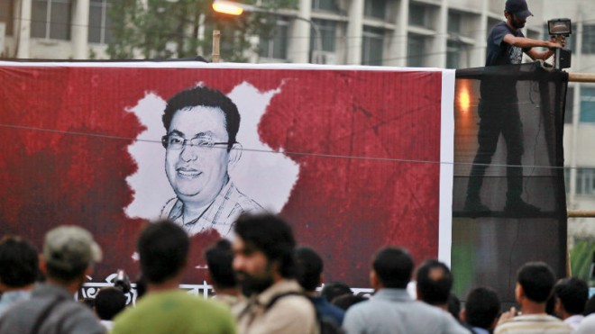 A Bangladeshi activist sets up a light on a poster displaying a portrait of Avijit Roy as others gather during a protest against the Roy in Dhaka, Bangladesh, Friday, Feb. 27, 2015. Roy, a prominent Bangladeshi-American blogger known for speaking out against religious extremism was hacked to death as he walked through Bangladesh's capital with his wife, police said Friday. (AP Photo/A.M. Ahad)