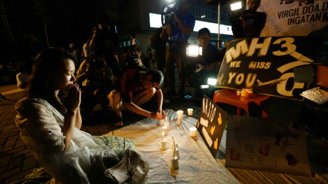 Kelly Wen, wife of Chinese passenger aboard the missing Malaysia Airlines Flight MH370 prays during an event to mark one year anniversary of the plane disappearance, during a candlelight vigil for passengers onboard the missing Malaysia Airlines Flight MH370 in Kuala Lumpur, Malaysia, on Friday, March 6, 2015. (AP Photo/Vincent Thian)