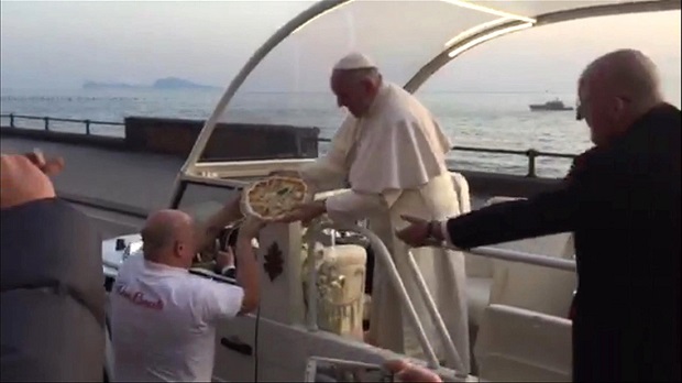 IN this image taken from video taken Saturday March 21, 2015 made available by Roberto Biscardi  shows Pope Francis receiving a pizza from Enzo Cacialli  in Naples Italy Saturday March 21, 2015.   Pizza maker Enzo Cacialli had a pie on hand as  Pope Francis sped by the Naples waterfront Saturday during his one-day visit to the city famous for its pizza. In a video made by a co-worker at the "Don Ernesto" pizzeria, Cacialli got close enough to the popemobile to make the delivery as the crowd behind him cheers.  (AP Photo/Roberto Biscardi) TV OUT