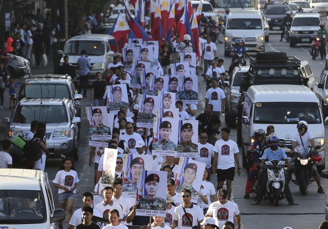 Family and supporters march as they hold some of the pictures of the 44 police commandos killed during a recent operation against Southeast Asia's top terrorist suspect Malaysian Zulkifli bin Hir, also known as Marwan, as they join a "Sympathy Walk" in suburban Quezon City on March 8, 2015. President Aquino will discuss the Mamasapano incident in his speech at the Philippine National Police Academy on Thursday, March26, and he believes it will end the controversy that has sunk his presidency in a crisis just as he is about to finish his term.  AP PHOTO/AARON FAVILA 