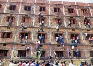 FILE - In this Wednesday, March 18, 2015 file photo, Indians climb the wall of a building to help students appearing in an examination in Hajipur, in the eastern Indian state of Bihar. Education authorities in eastern India say 600 high school students have been expelled after they were found to have cheated on pressure-packed 10th grade examinations. AP Photo/Press Trust of India