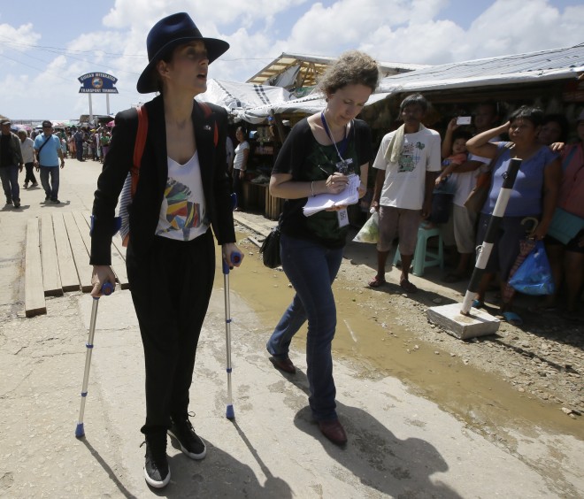 French actress Marion Cotillard is interviewed by a journalist as she walks with crutches during French President Francois Hollande's visit to the typhoon-ravaged Guiuan township, in Eastern Samar province in the central Philippines Friday, Feb. 27, 2015. Hollande's two-day state visit focuses on climate change. AP