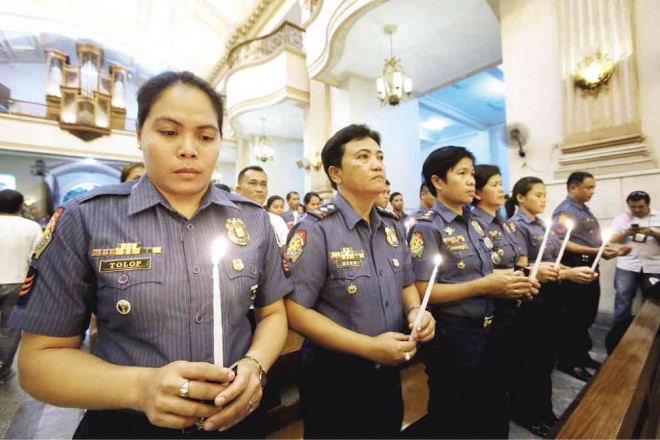 POLICEMEN and women hold lighted candles during Mass for the 44 police commandos who, protesters said, were sent to their deaths in a clandestine operation to kill or capture international terrorist Marwan. JUNJIE MENDOZA/CEBU DAILY NEWS 