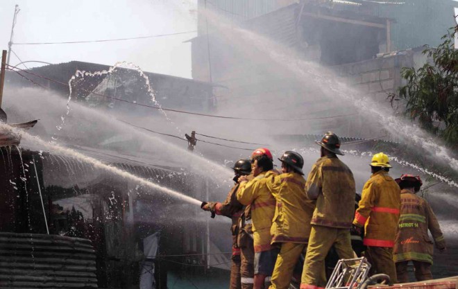 ARMS on each other’s shoulders as if to lend their strength to the main man wielding the nuzzle of the hose, firefighters battle the second fire that struck the Parola Compound in Tondo, Manila, Tuesday afternoon. Another blaze, which displaced more than 6,000 families, broke out in the area Monday night. Joan Bondoc 