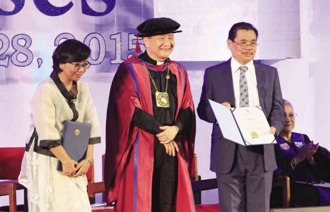 Prof. Miriam Coronel-Ferrer (left) and Moro Islamic Liberation Front peace panel chair Mohagher Iqbal (right) receive from university president Fr. Roberto Yap, SJ, (center) the Fr. William F. Masterson, SJ, Award during commencement exercises at  Xavier University in Cagayan de Oro City. JB R. DEVEZA/INQUIRER MINDANAO 